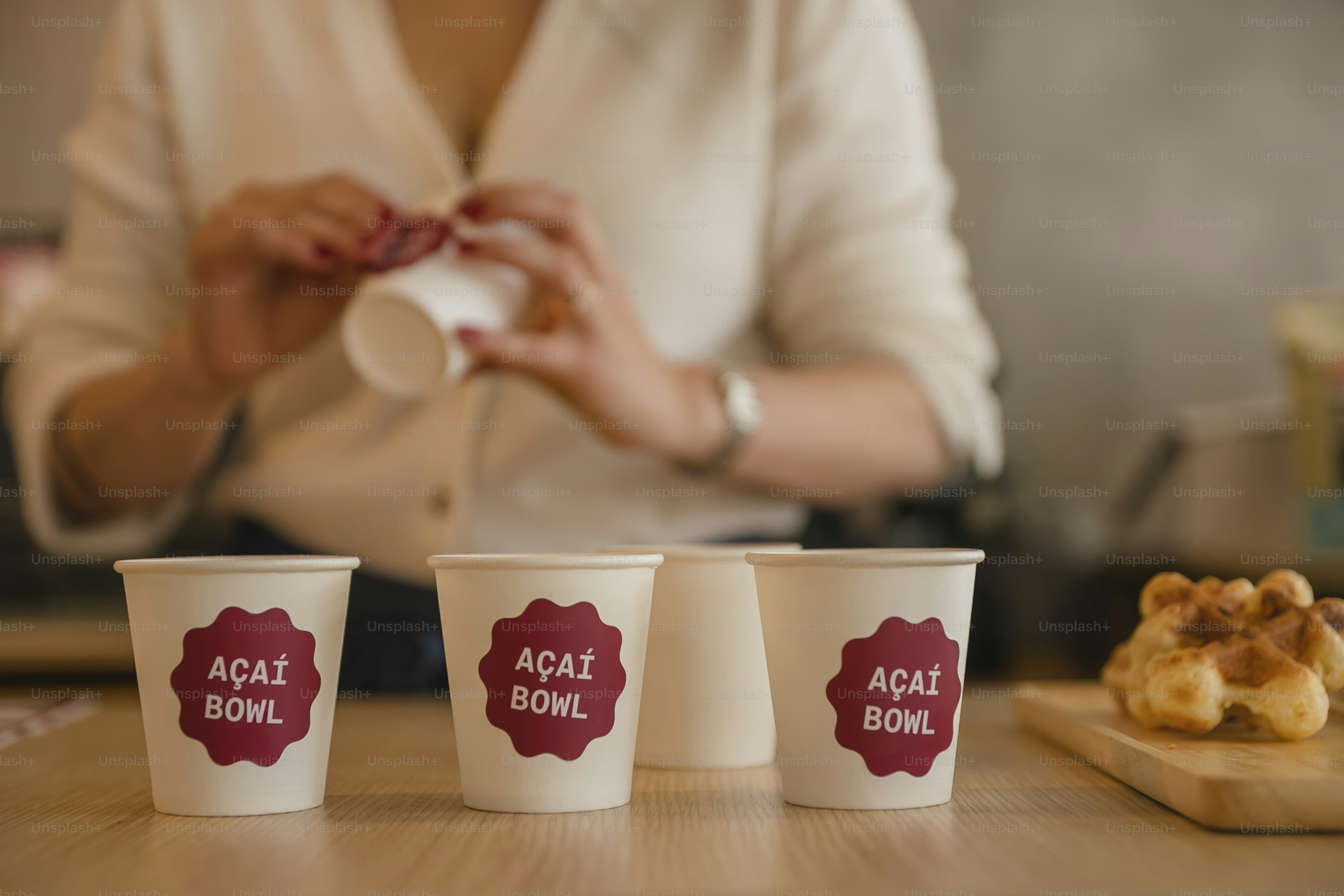 Una mujer sostiene una servilleta frente a tres tazas