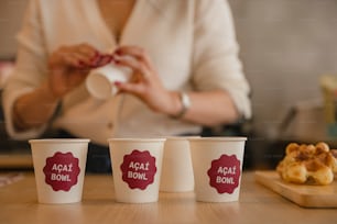 a woman is holding a napkin in front of three cups