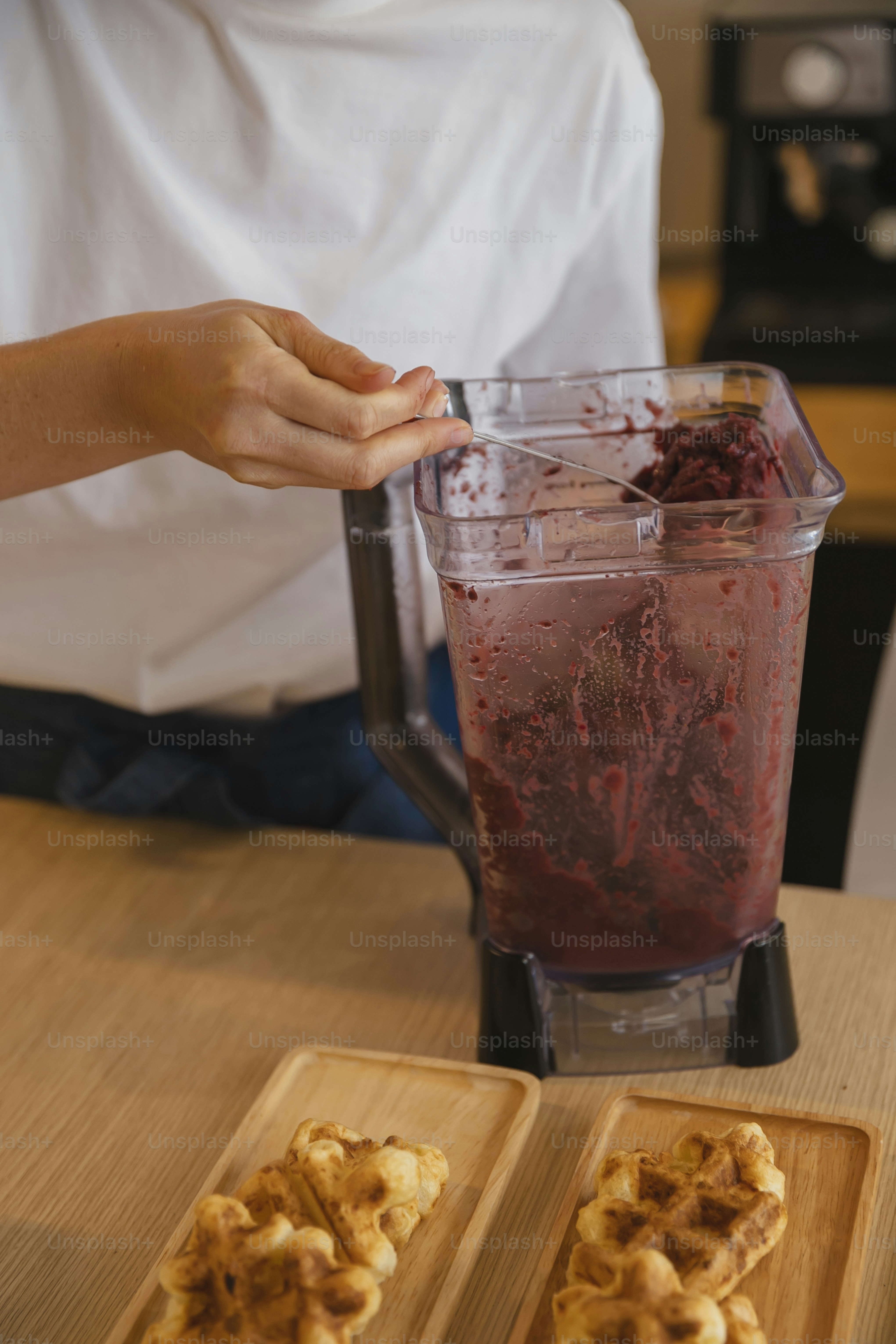 Una licuadora llena de líquido rojo encima de una mesa de madera