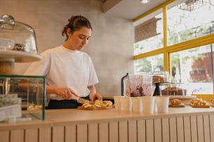 a woman in a white shirt preparing food at a counter
