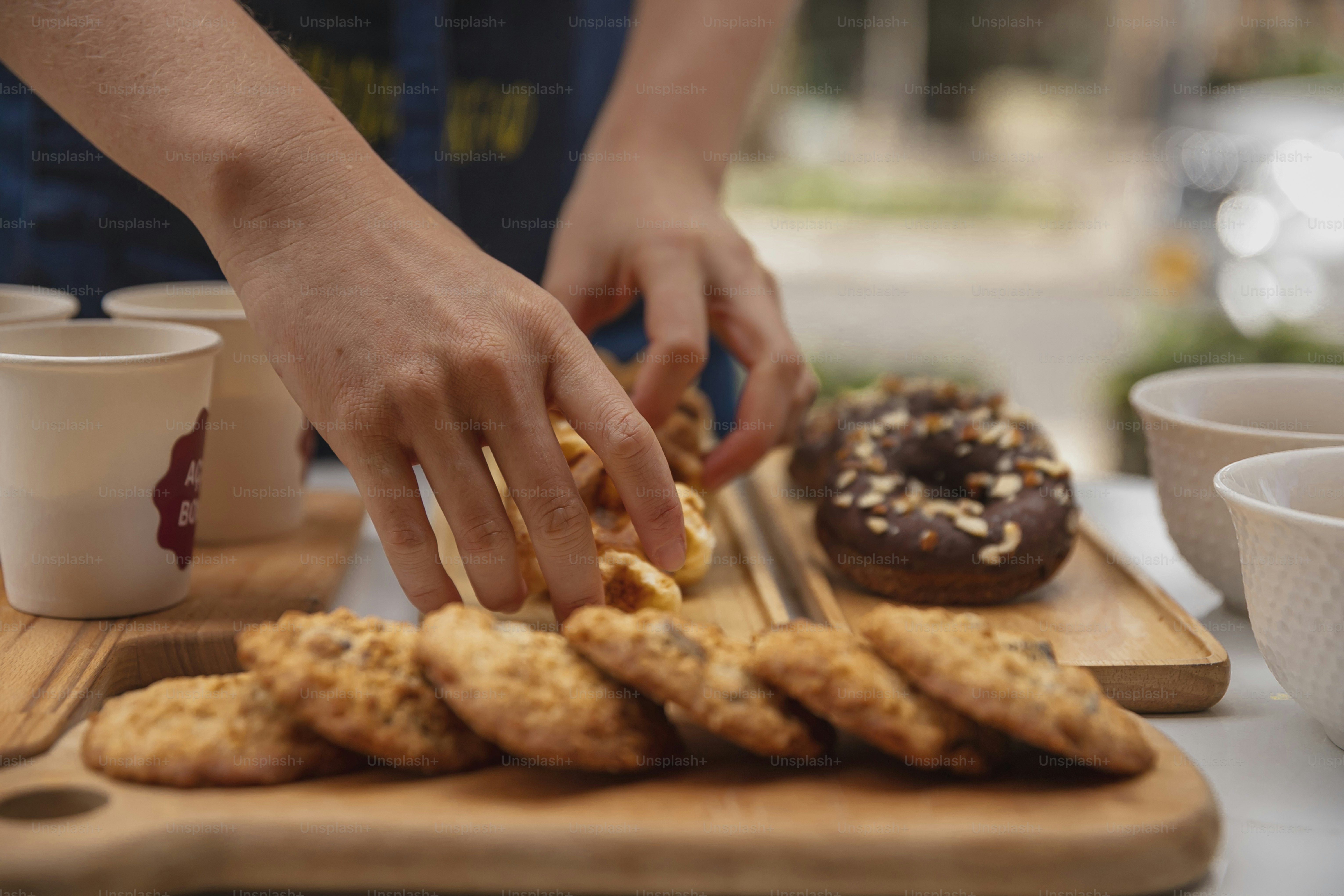 a person reaching for a donut on a cutting board