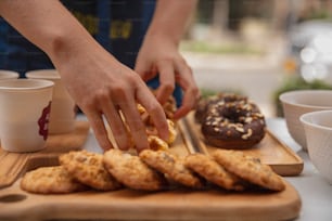 a person reaching for a donut on a cutting board