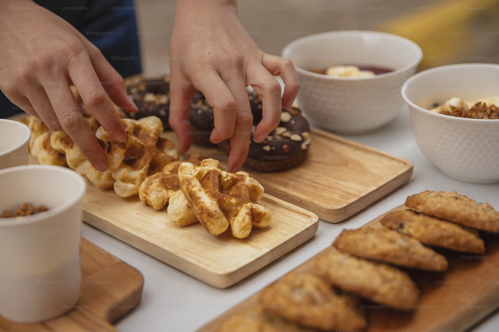 a person reaching for a donut on a cutting board