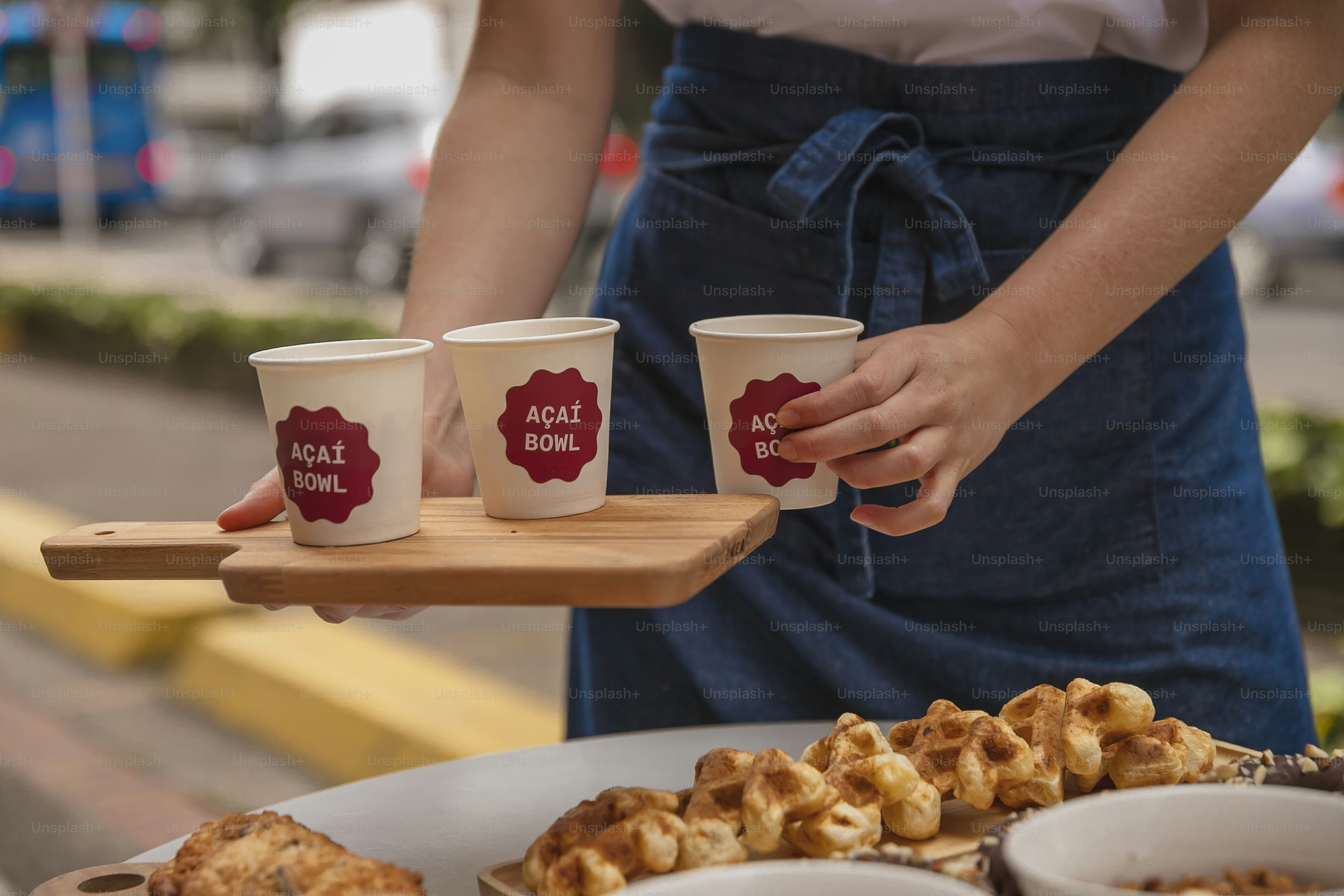 eine person, die ein tablett mit drei tassen kaffee hält