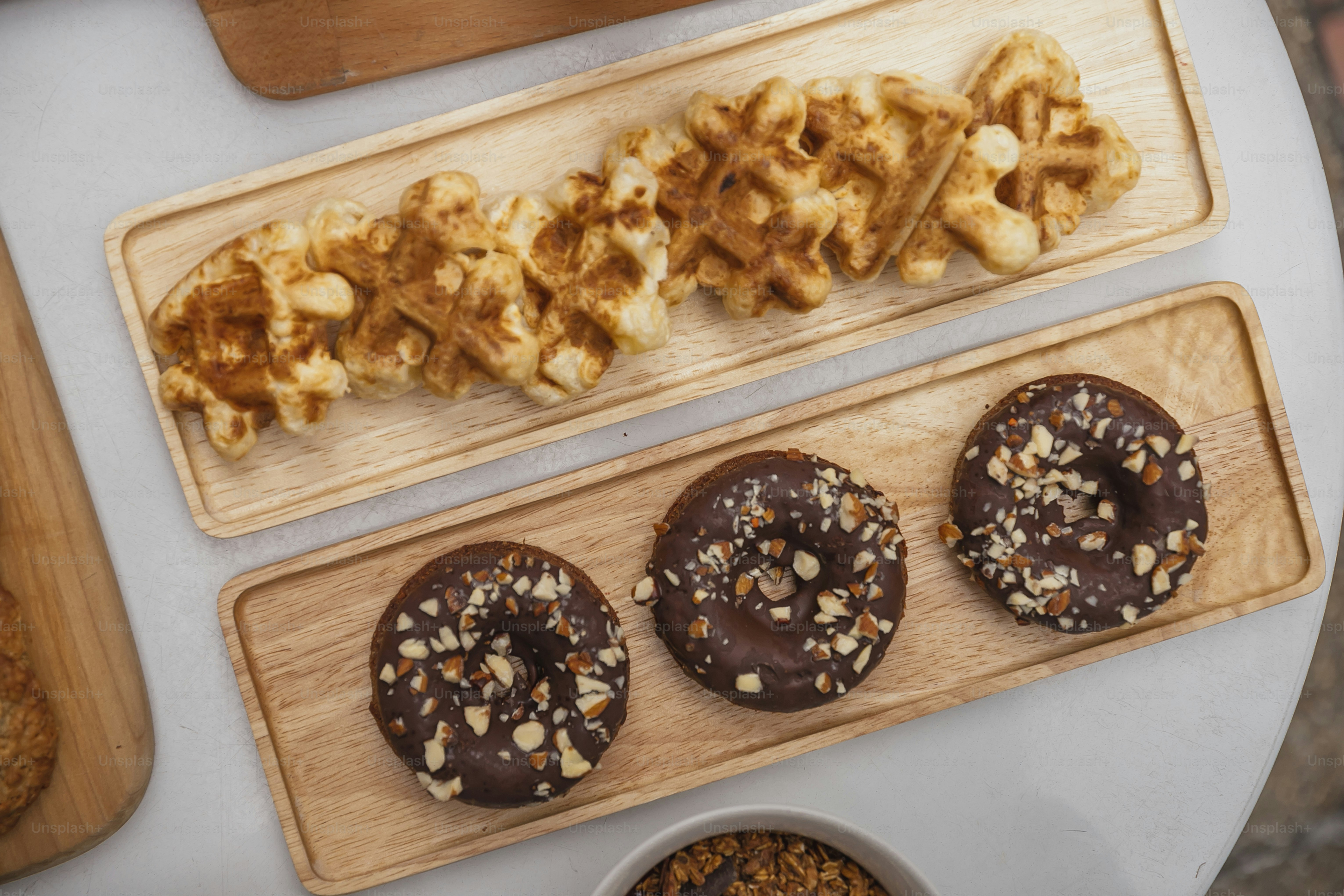 a table topped with donuts and waffles next to a bowl of cereal