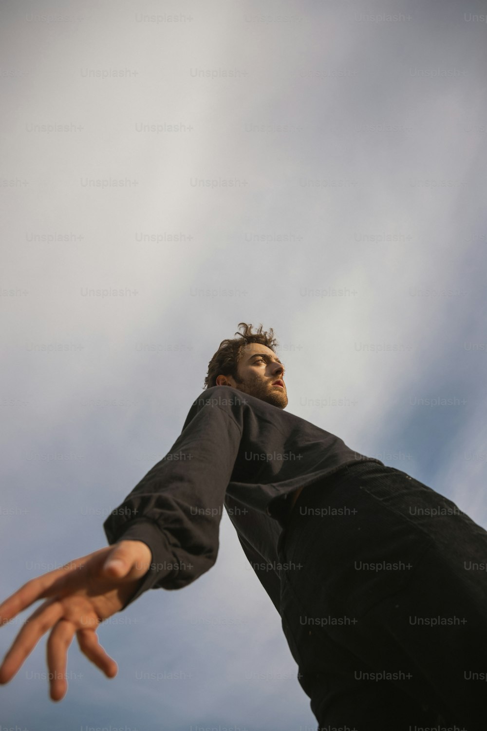 a man reaching up into the air to catch a frisbee