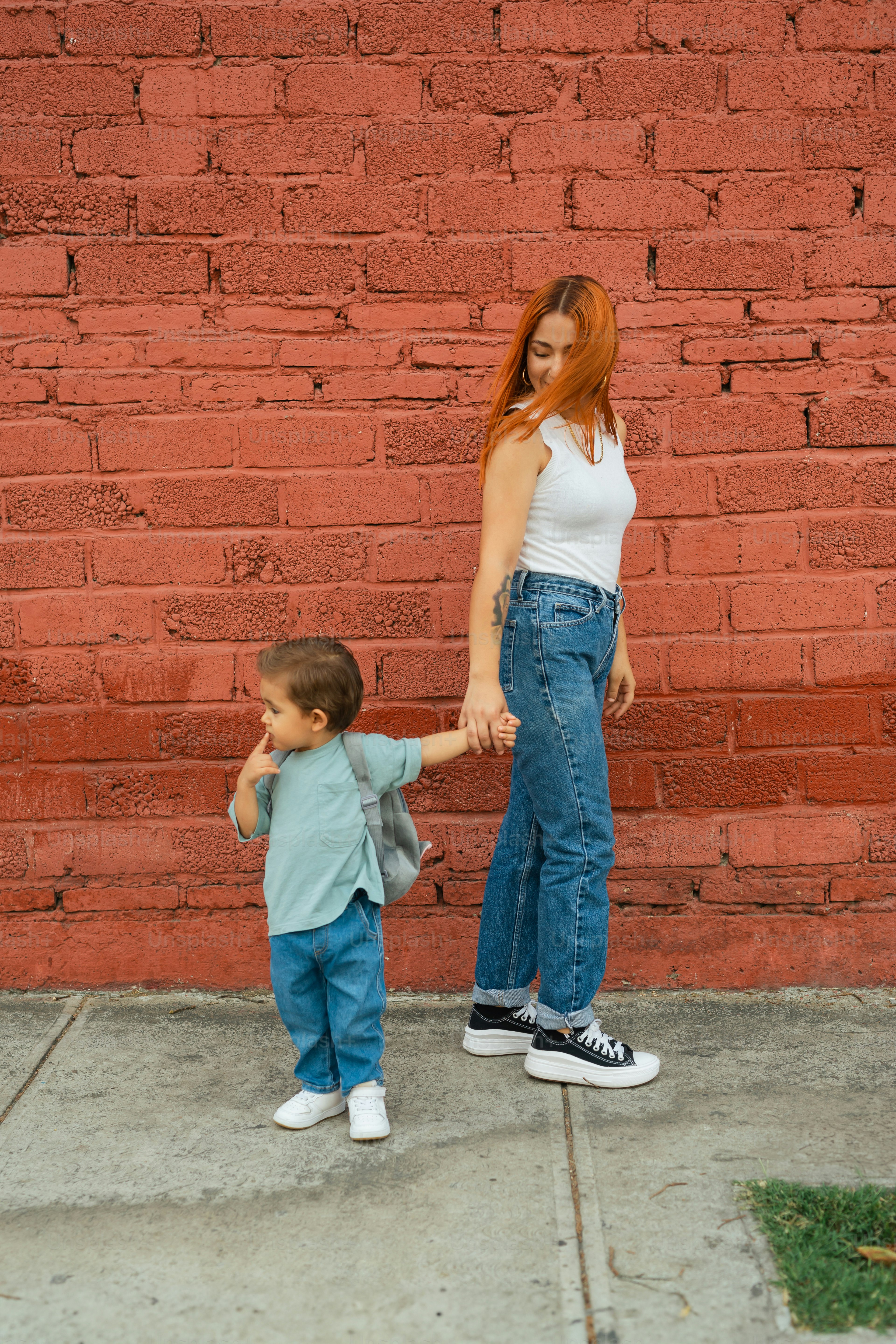 a woman holding the hand of a small boy