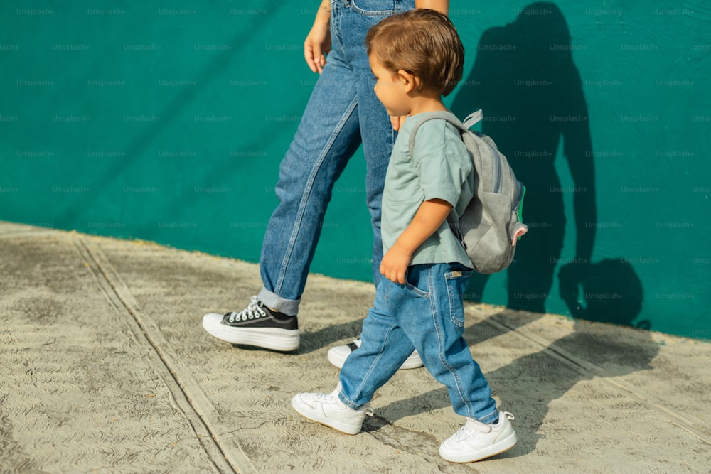 Un ragazzino che cammina lungo un marciapiede accanto a una donna
