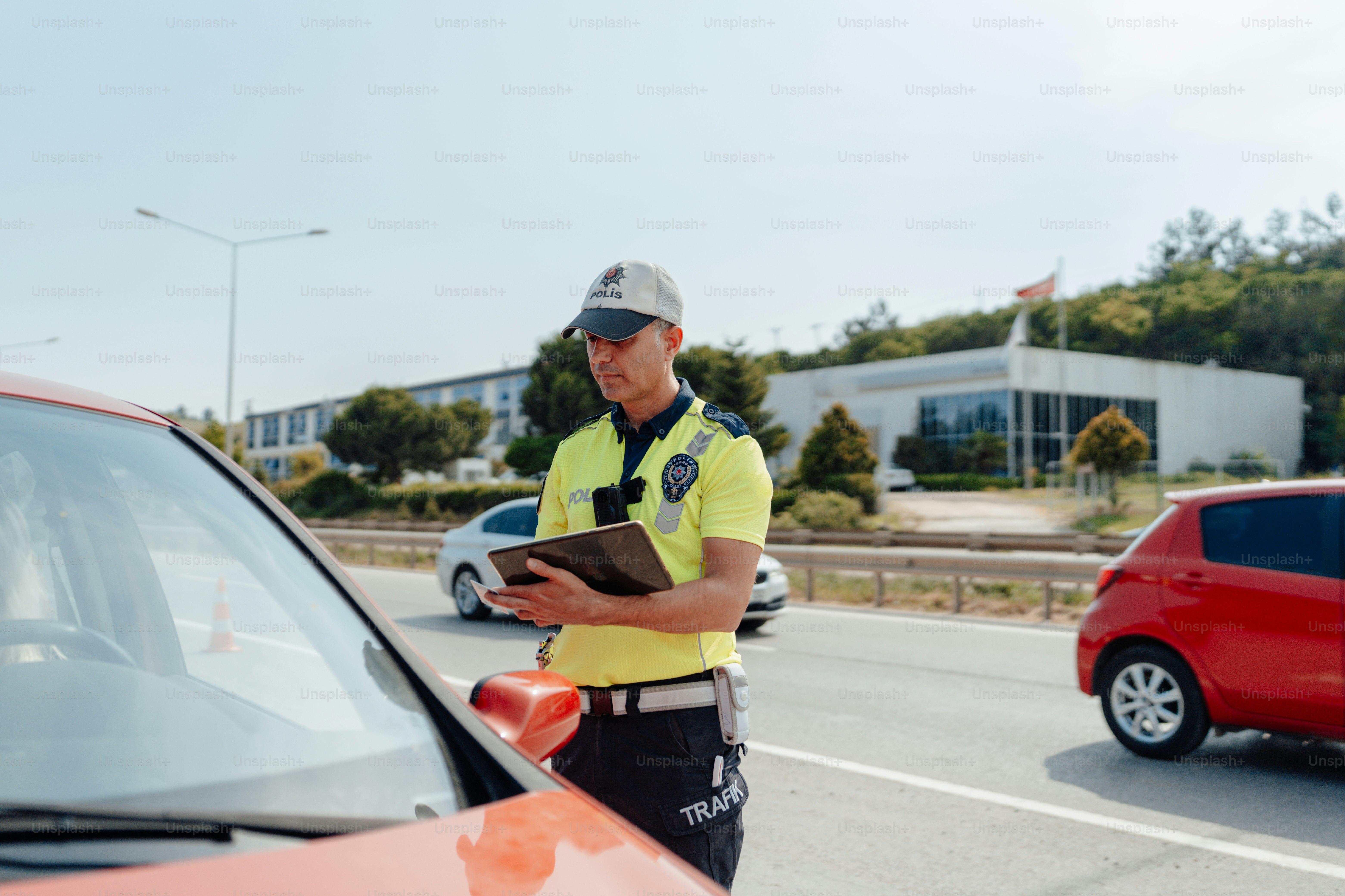 a man standing next to a red car holding a clipboard