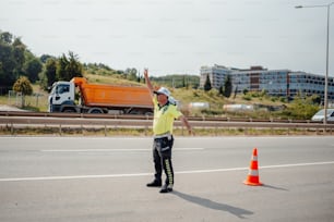 a man standing on the side of a road next to a traffic cone