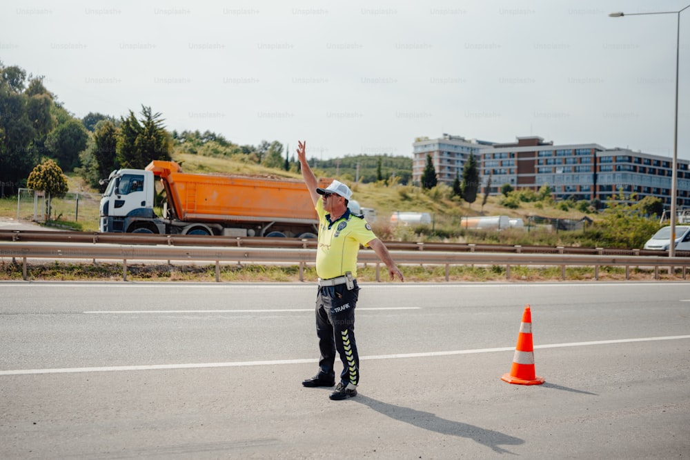 a man standing on the side of a road next to a traffic cone
