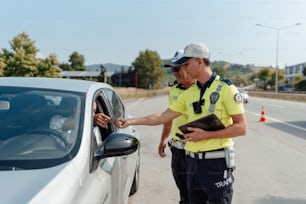 Ein Mann in Polizeiuniform, der neben einem Auto steht