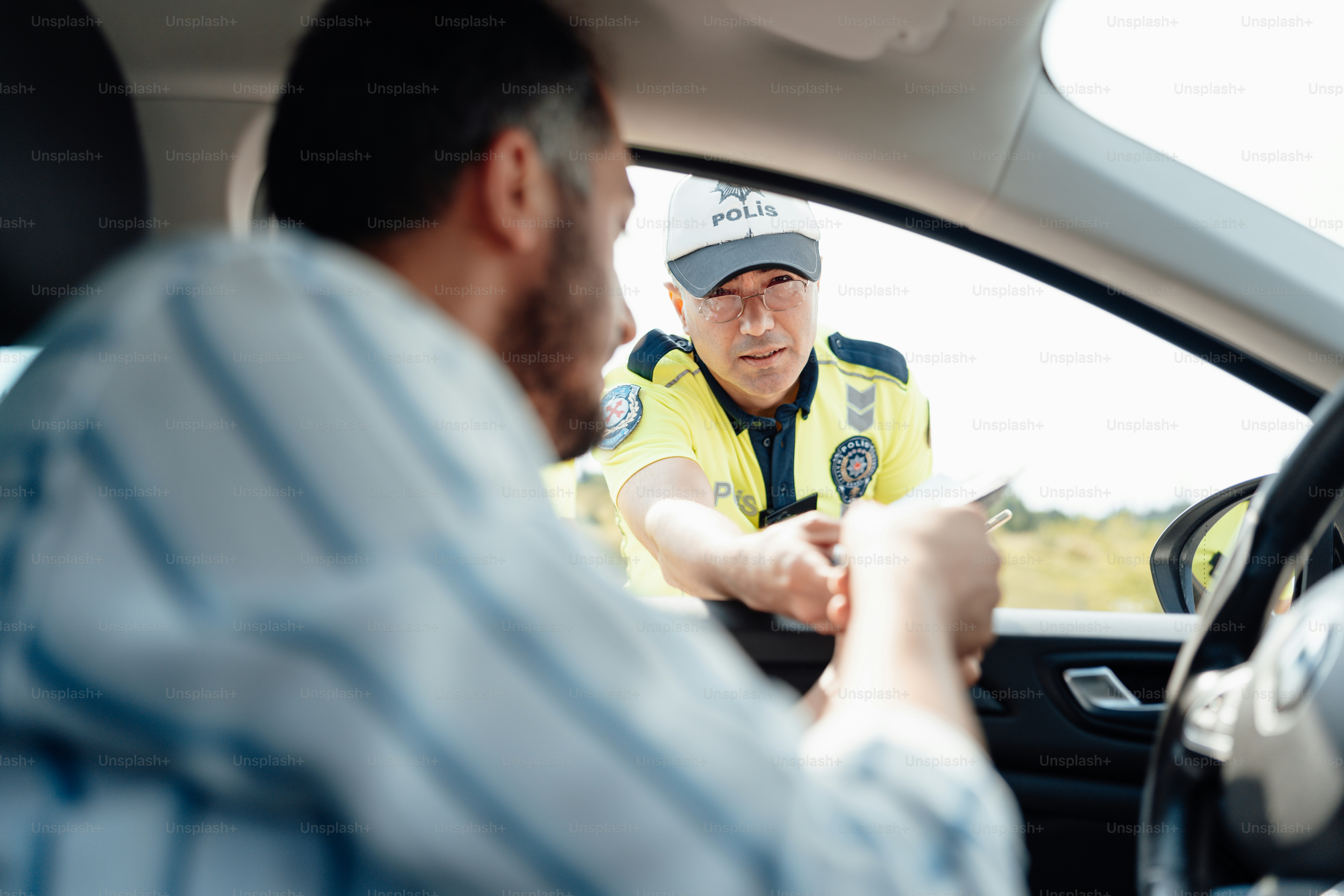 a man sitting in a car talking to another man