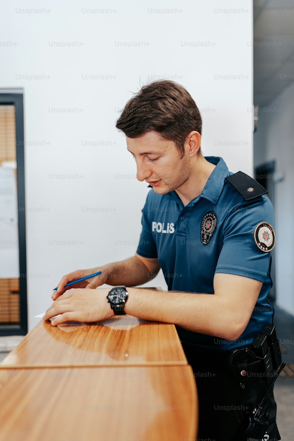 Ein Polizist, der mit einem Handy an einem Schreibtisch sitzt