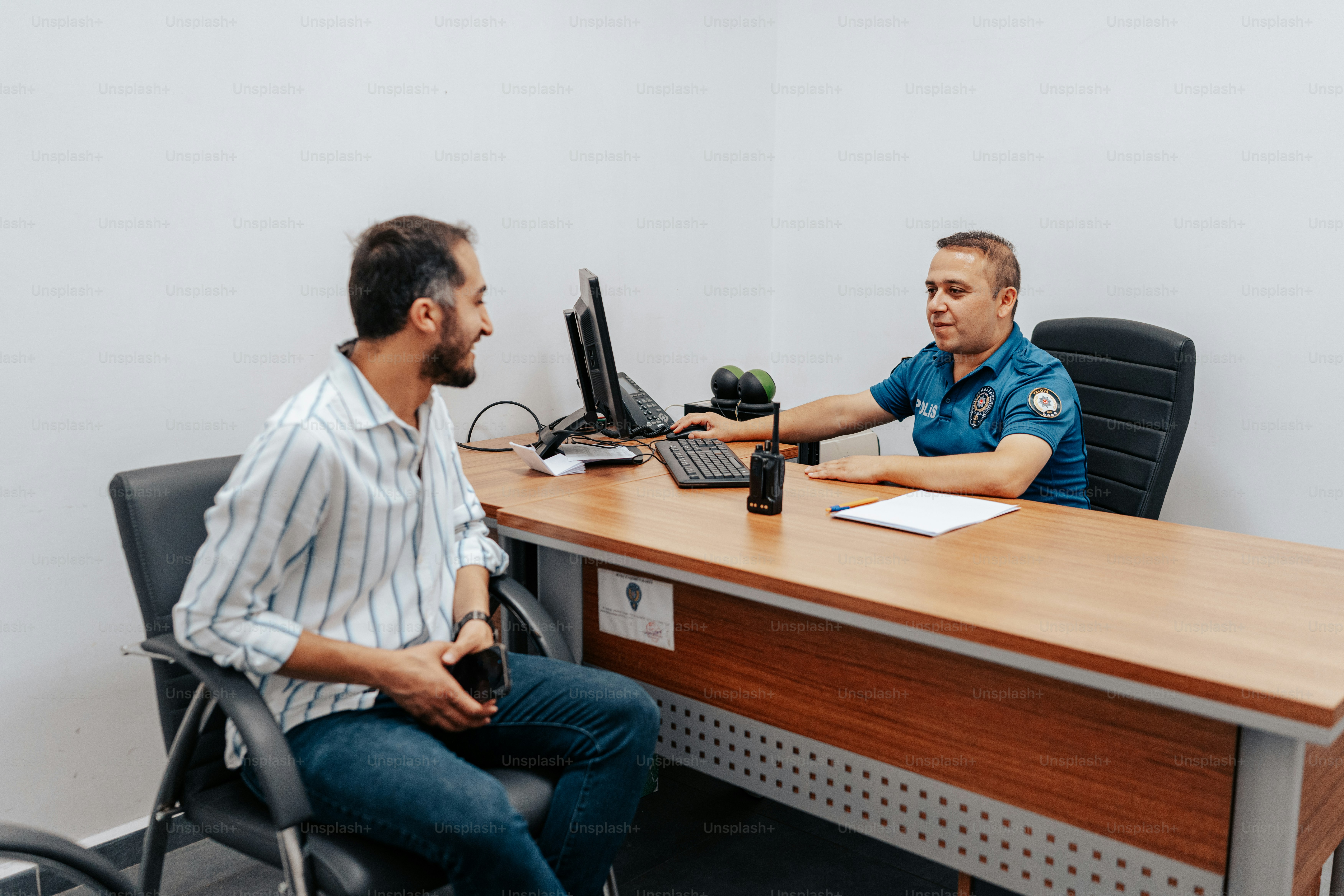 a man sitting at a desk talking to another man