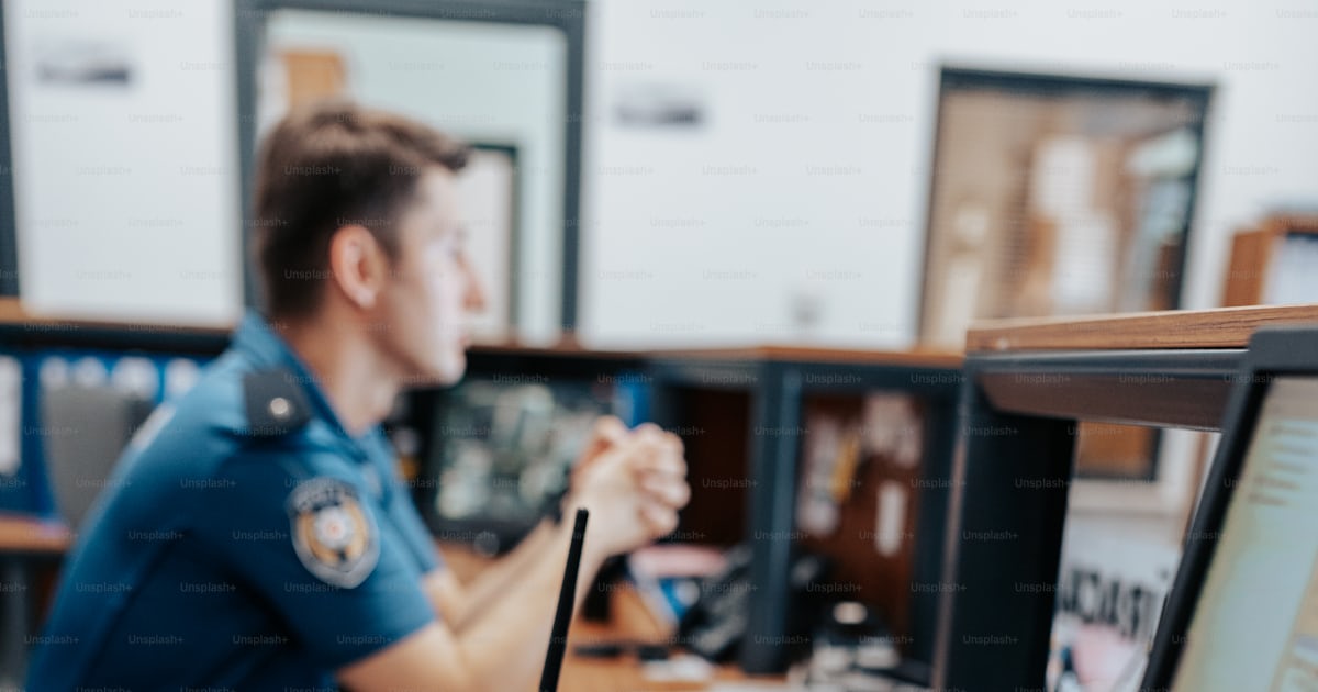 A man sitting at a desk with a laptop computer photo – Law enforcement ...