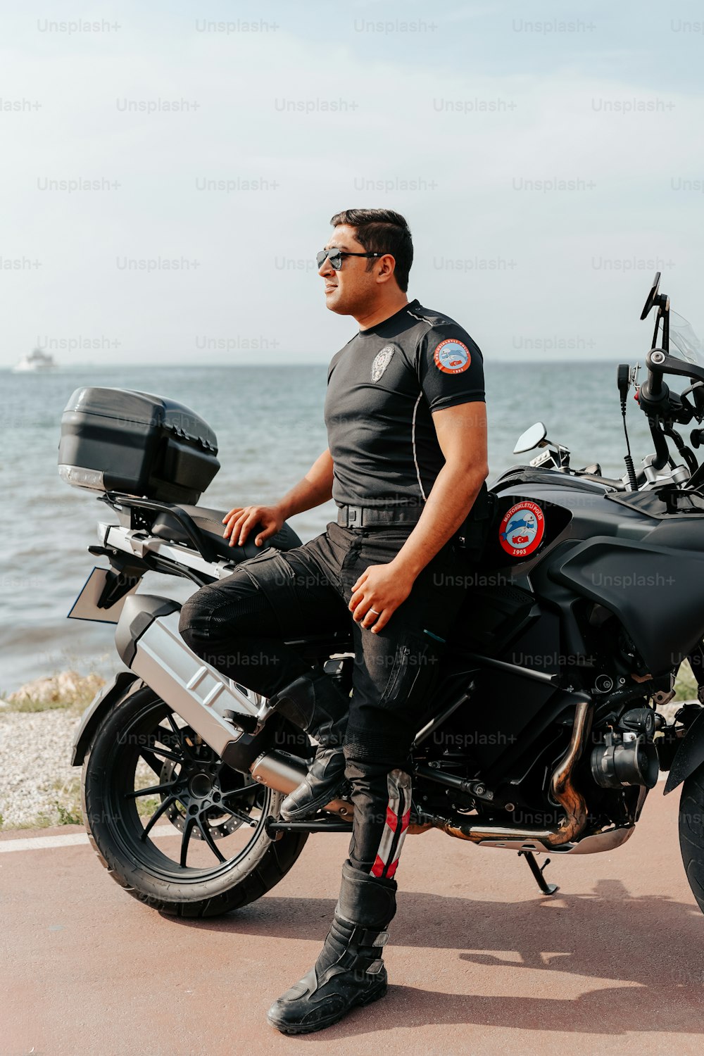 a man sitting on a motorcycle near the ocean