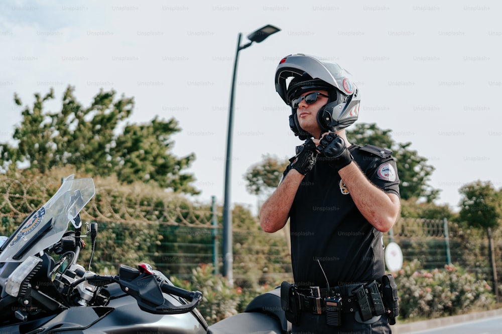 Un homme portant un casque et des gants debout à côté d’une moto