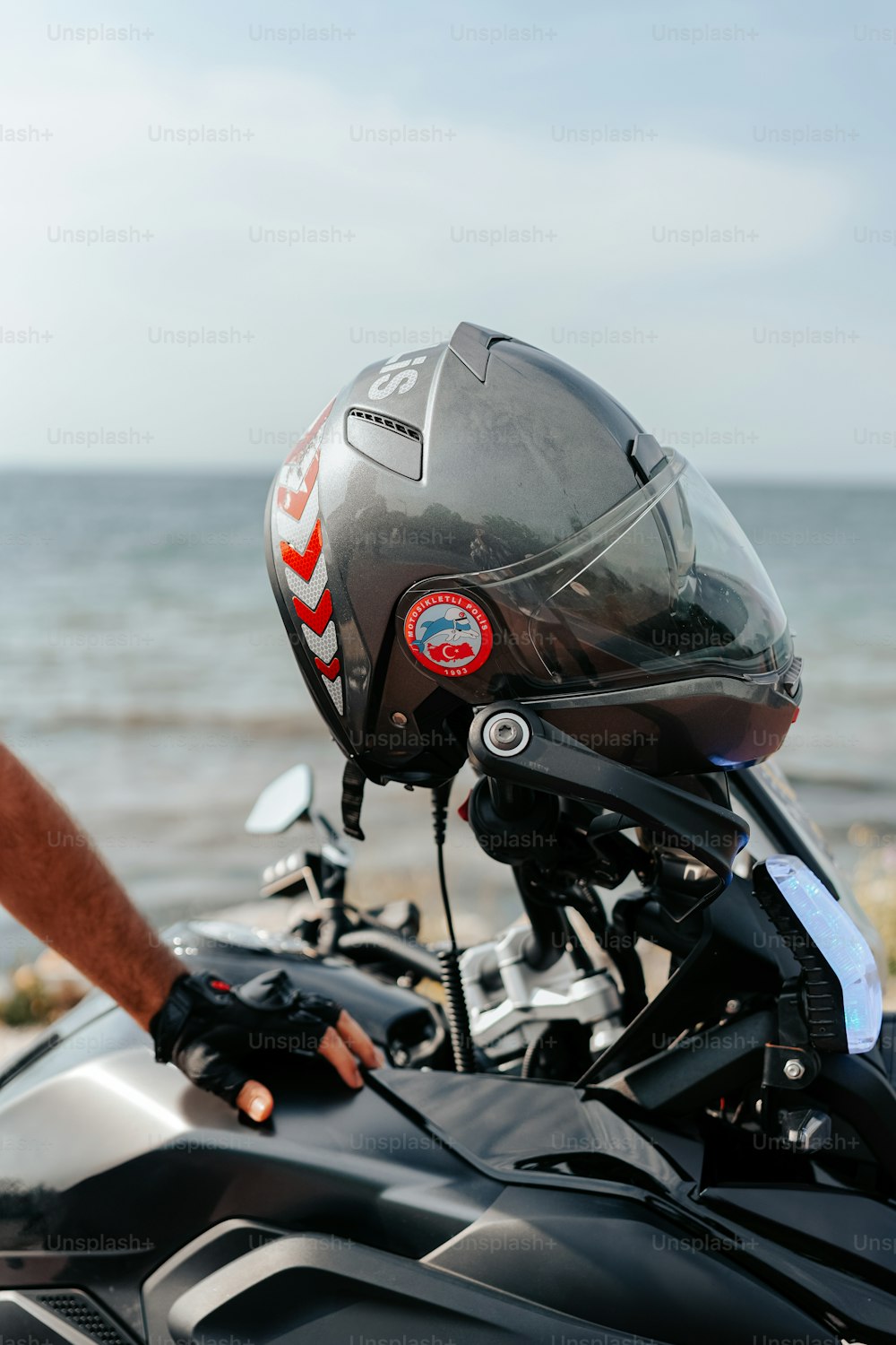 헬멧을 쓰고 해변에 주차된 오토바이