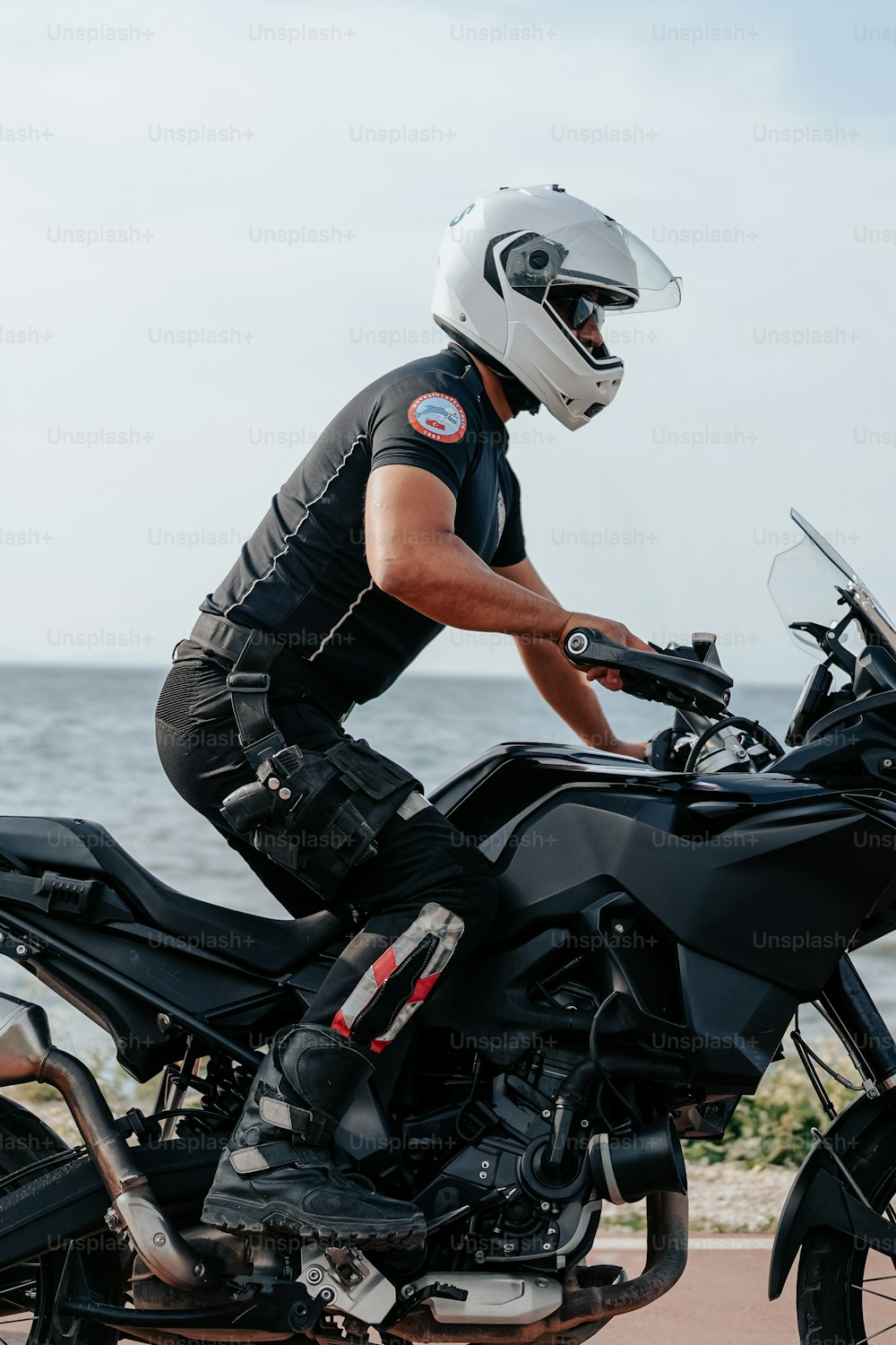 a man riding a motorcycle next to the ocean