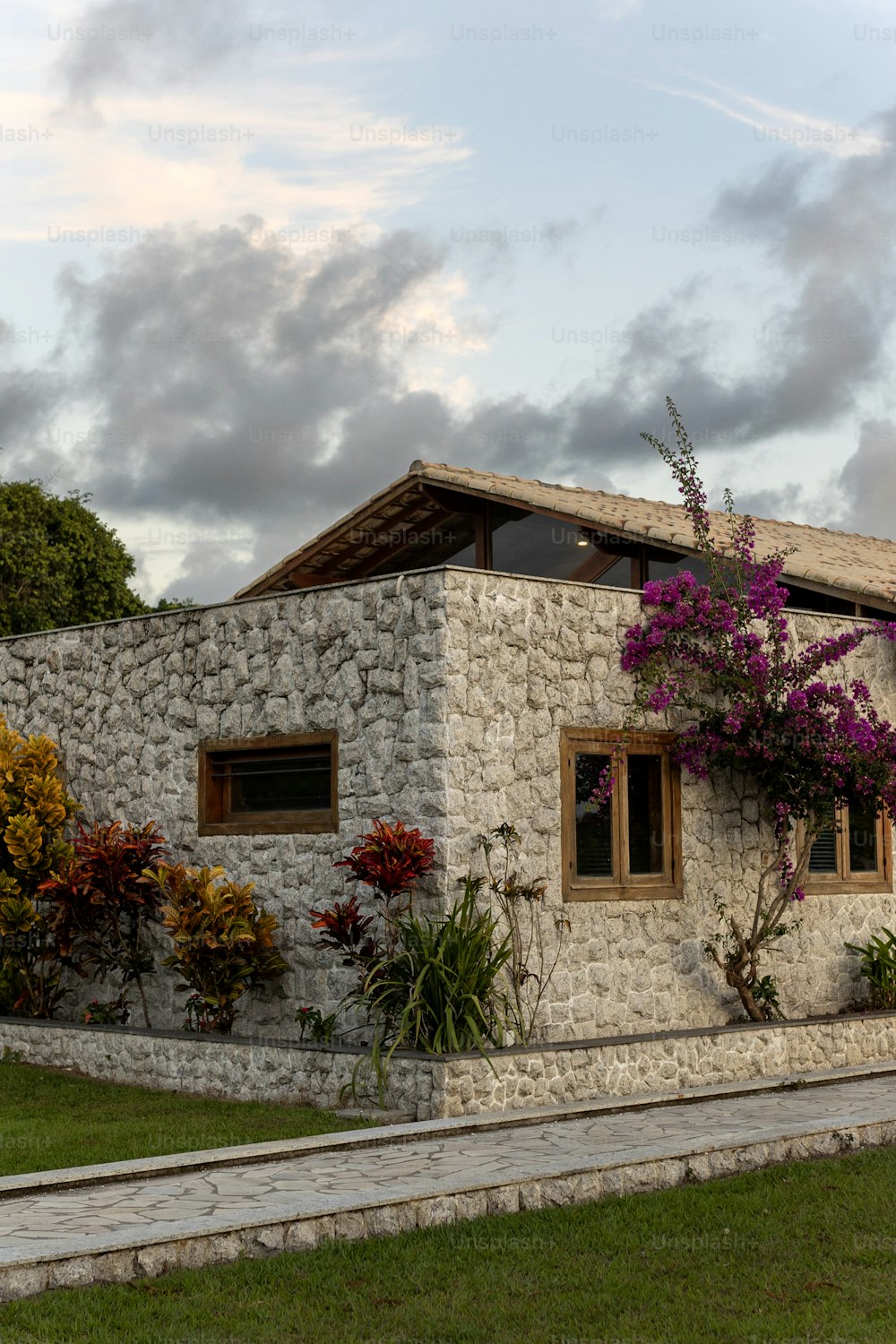 une maison en pierre avec des fleurs poussant sur le côté