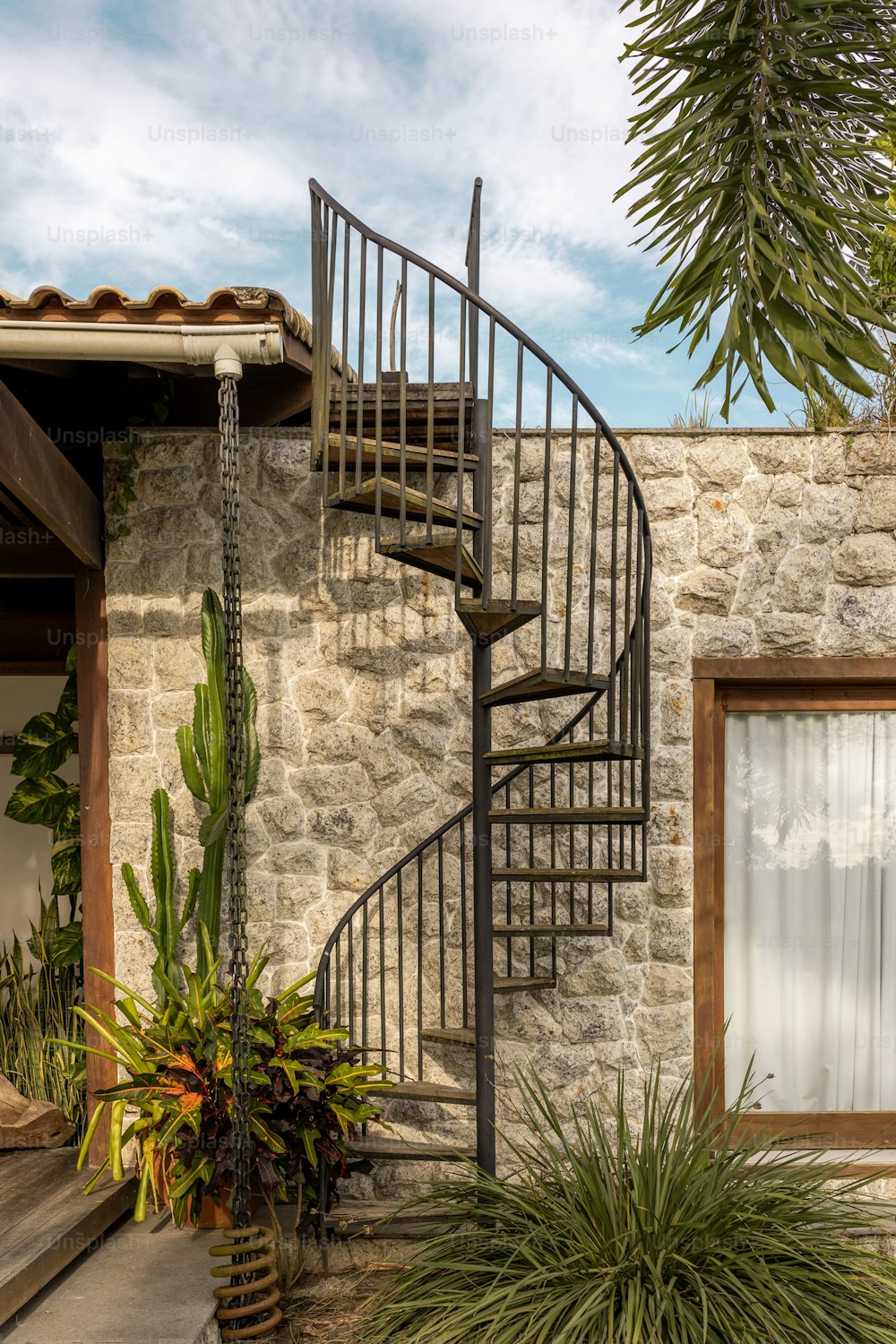 a metal spiral staircase next to a stone building