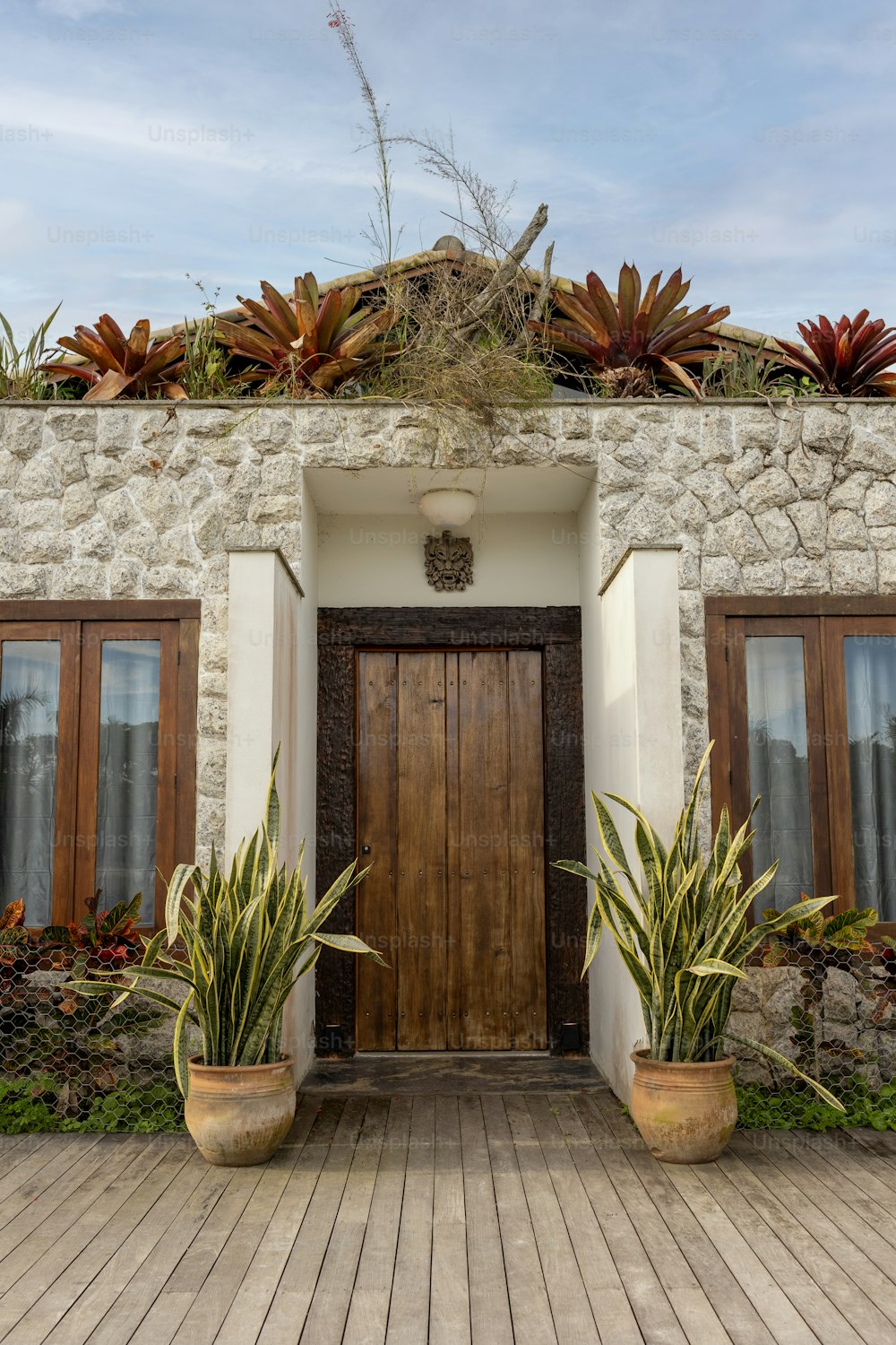 a house with a wooden door and two planters