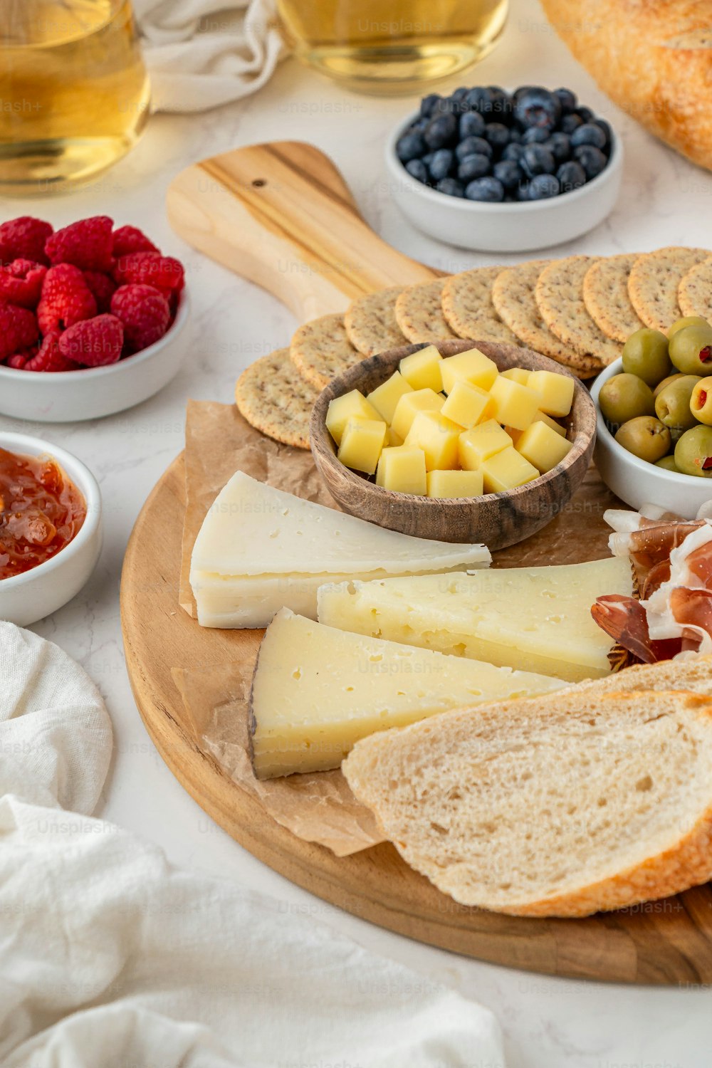 a platter of cheese, crackers, fruit, and bread