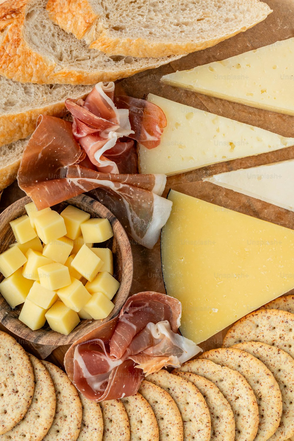 a platter of cheese, crackers, bread and meats