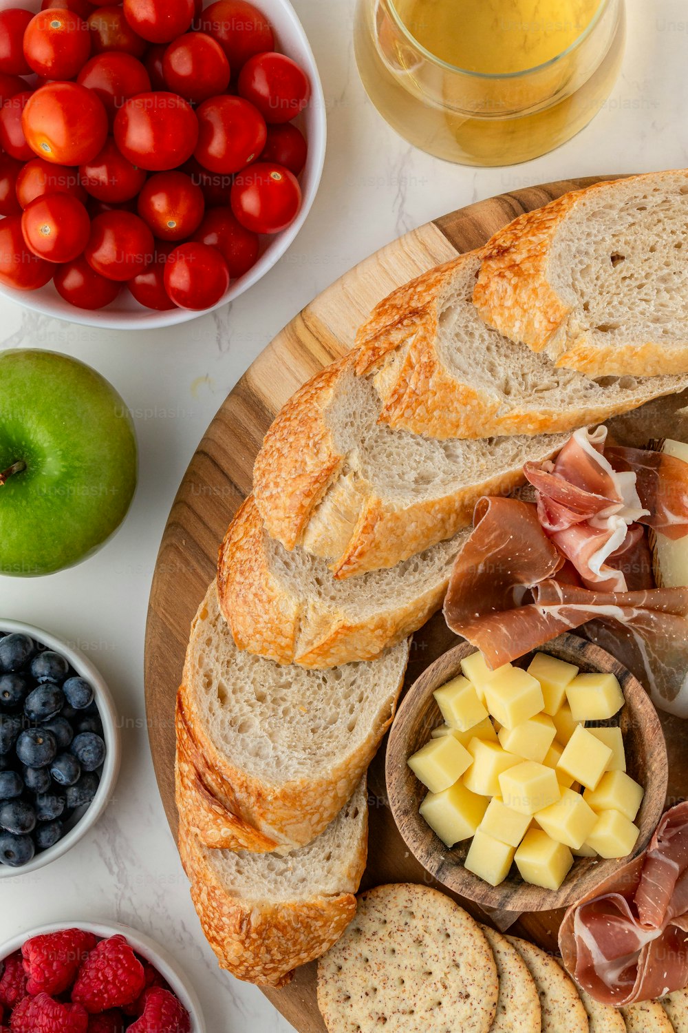 a platter of bread, fruit, cheese, and crackers