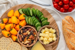 um prato de madeira coberto com queijo, bolachas e frutas