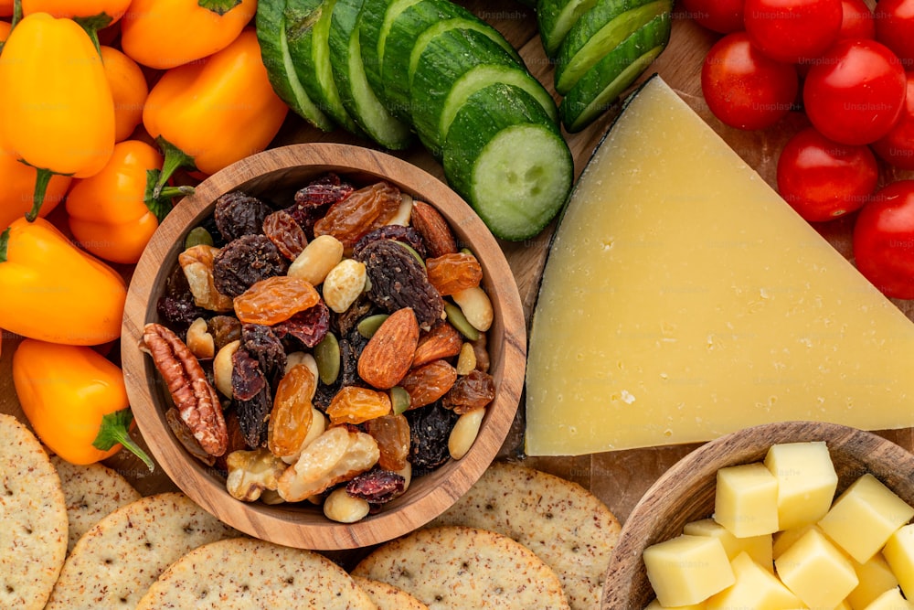a wooden bowl filled with fruit and nuts next to crackers