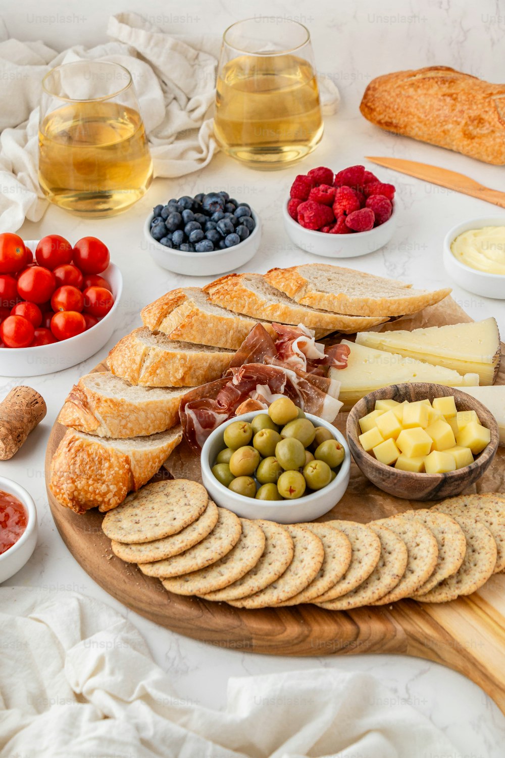 eine Platte mit Brot, Käse, Oliven, Erdbeeren, Erdbeeren