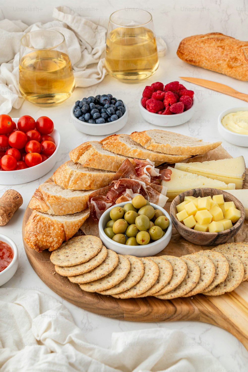 a platter of bread, cheese, olives, strawberries, strawberries