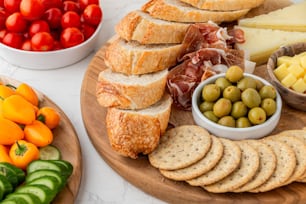 a platter of bread, cheese, olives, tomatoes, and crackers