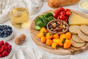 a plate of cheese, crackers, fruit and vegetables