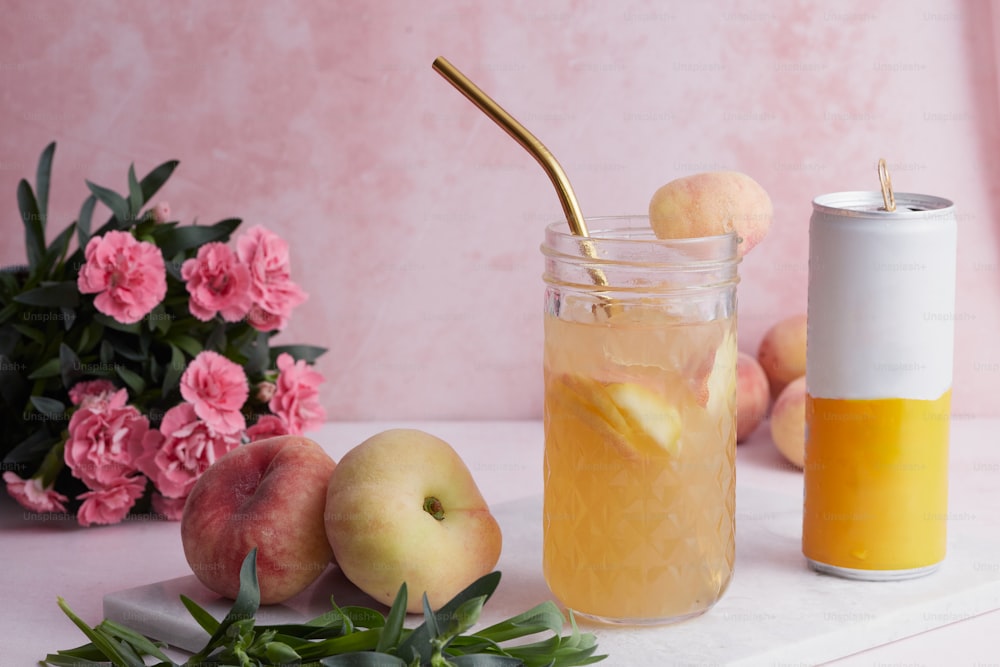 a jar of liquid next to a vase of peaches