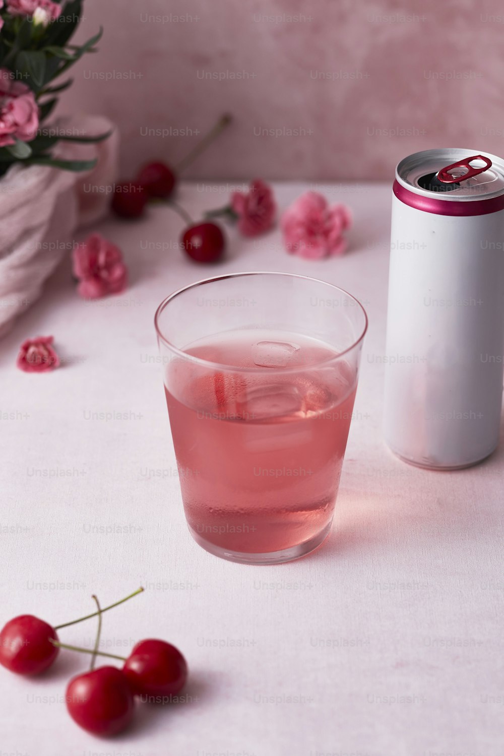 a glass of pink liquid next to a can of soda