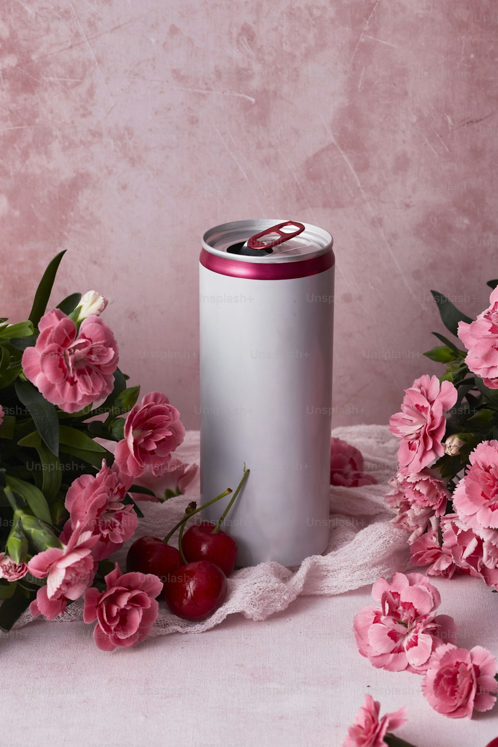 uma lata de refrigerante rodeada por flores cor-de-rosa