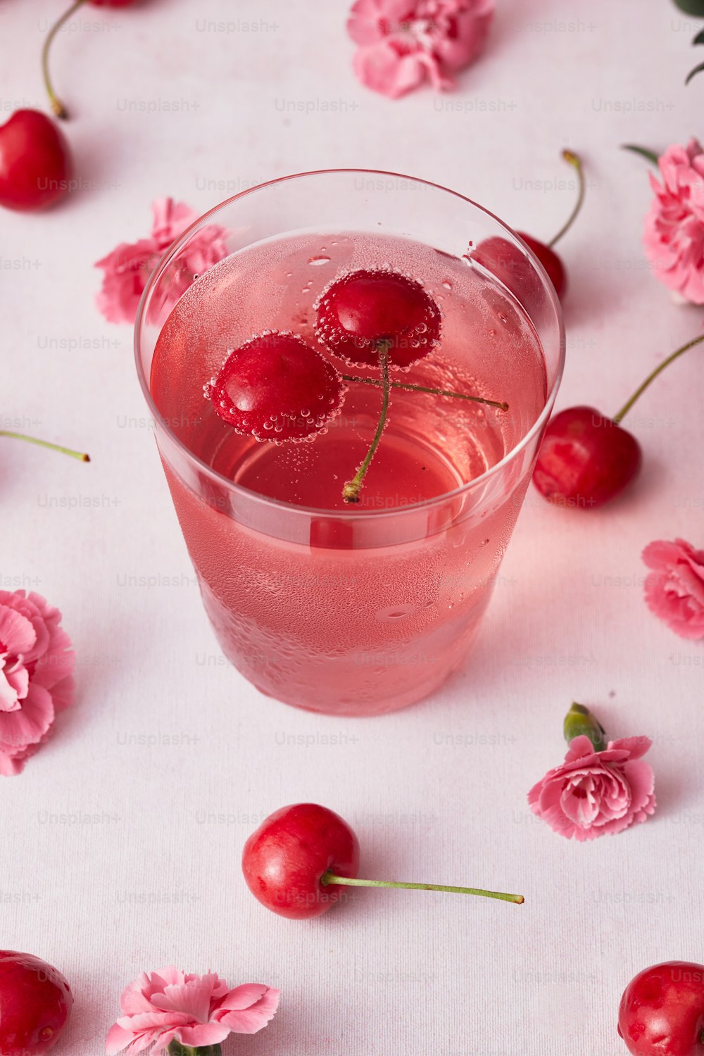 a pink drink with cherries on a table