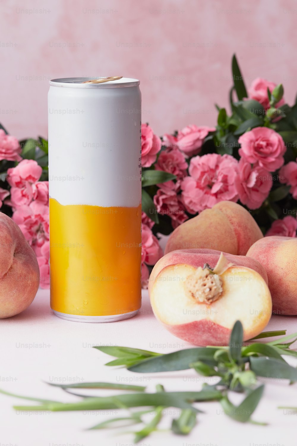 a can of peach juice next to peaches and flowers