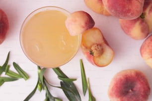 a glass of peach juice surrounded by peaches