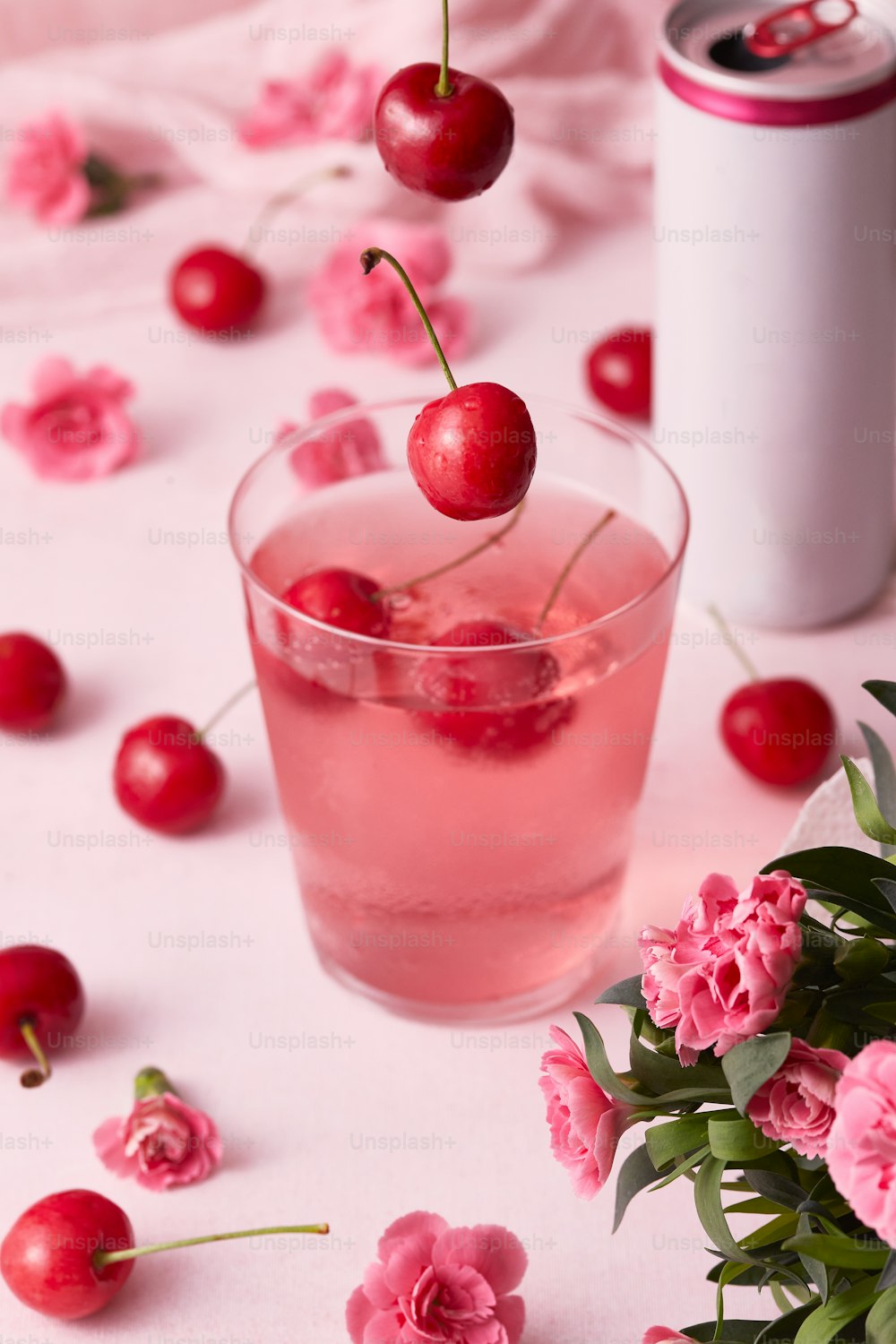 Une boisson rose avec des cerises sur une table