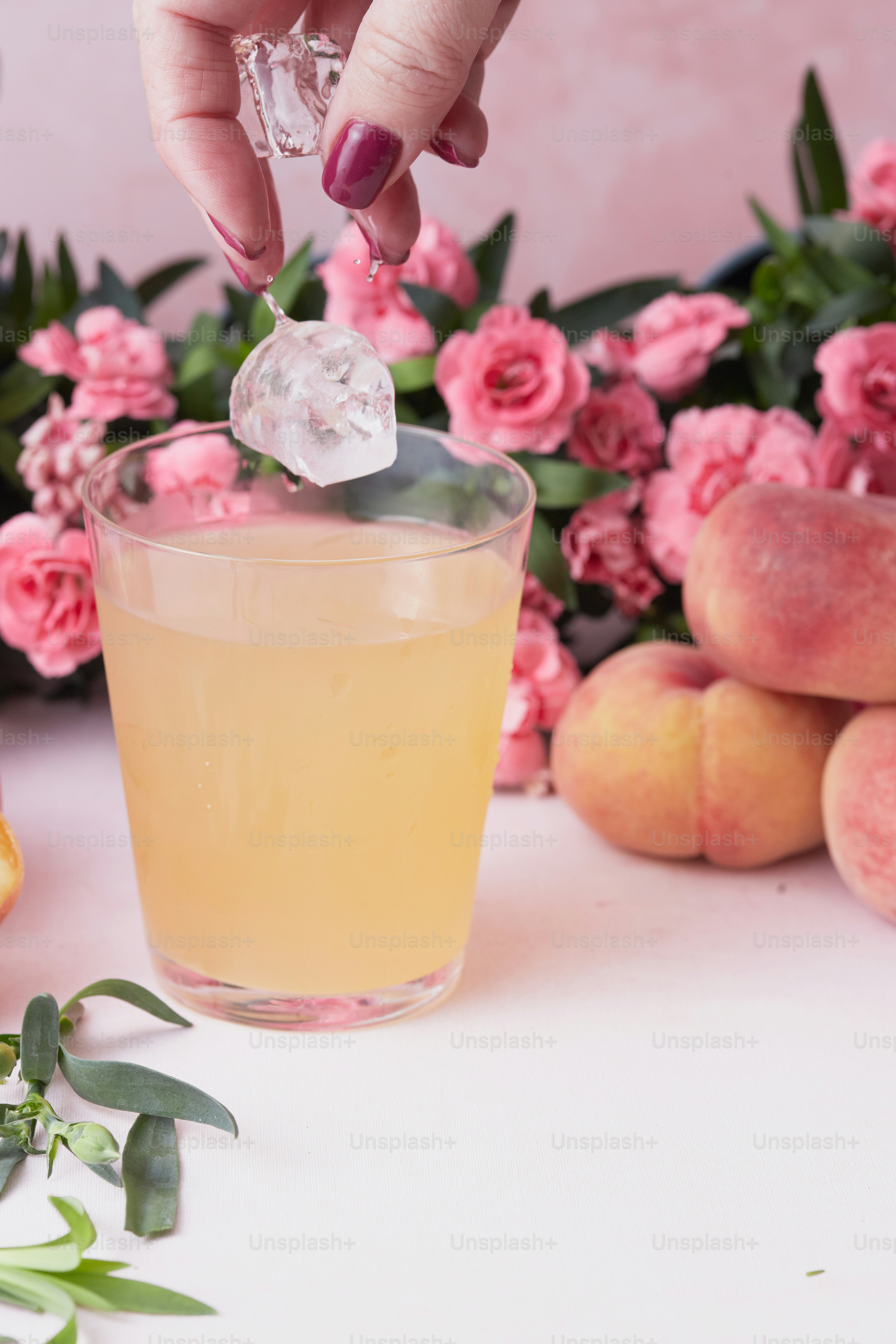 A person is putting a piece of ice into a glass photo Non alcoholic drinks Image on Unsplash