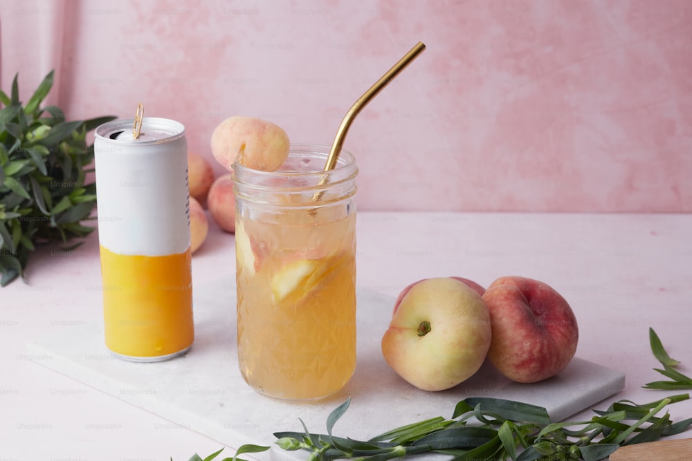 a jar filled with liquid next to a couple of peaches