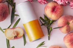 a can of apple cider next to peaches and flowers