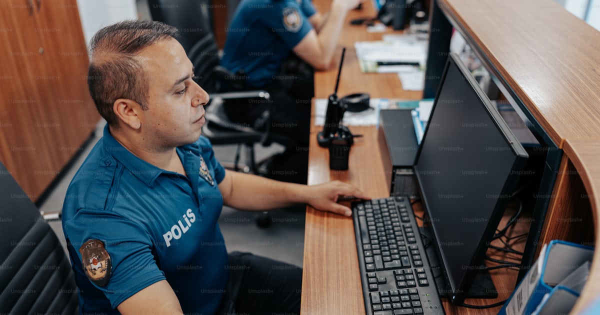 A police officer sitting in front of a computer photo – Police station ...