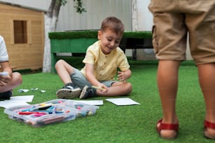 a young boy sitting on the ground playing with crayons
