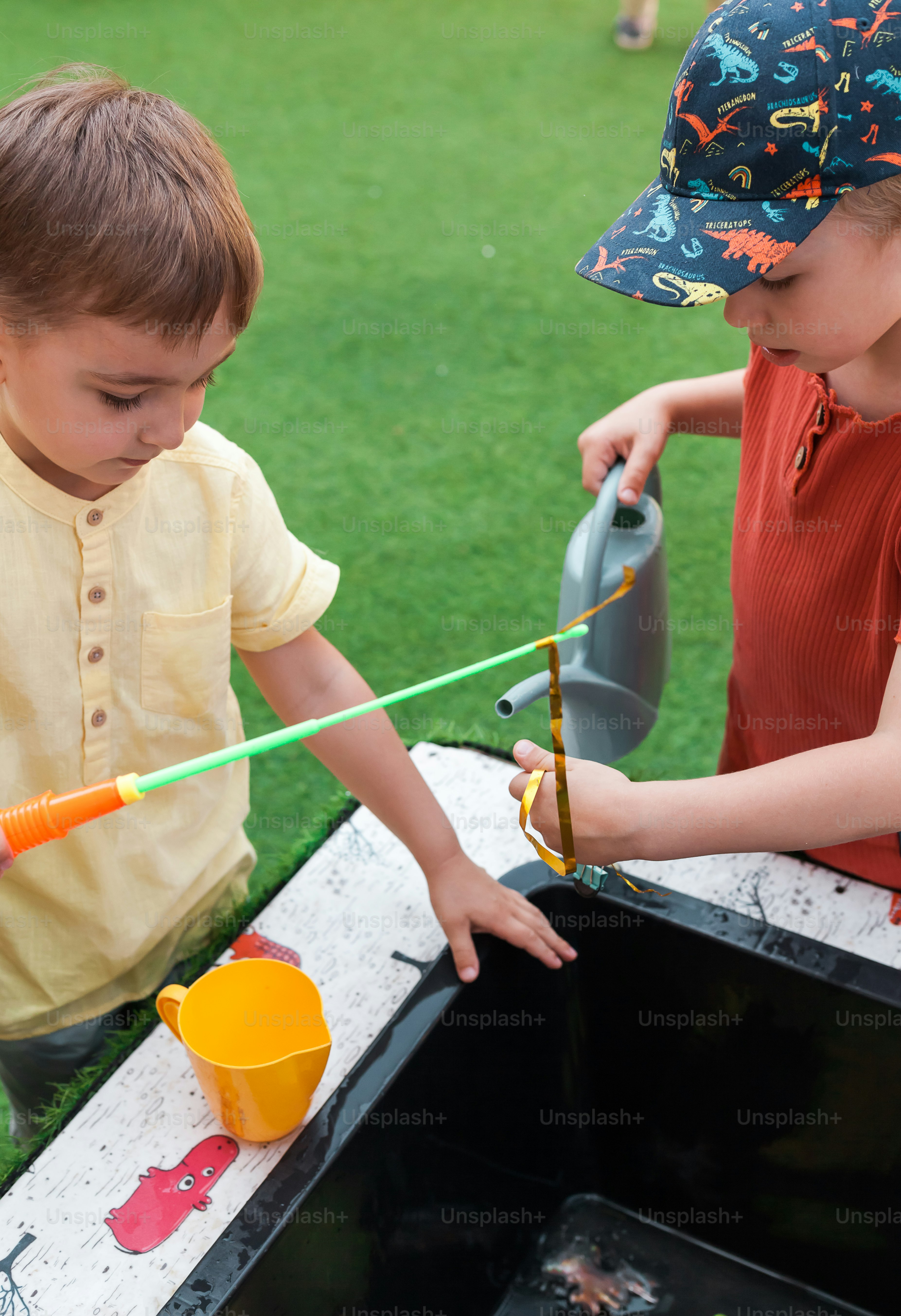 two young boys are playing with a water fountain