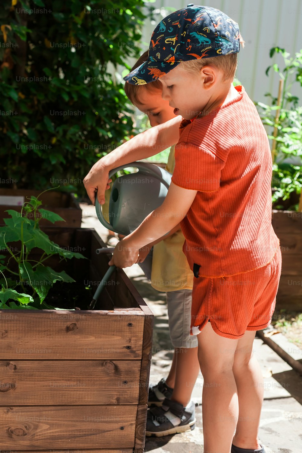 a young boy in an orange shirt and a hat